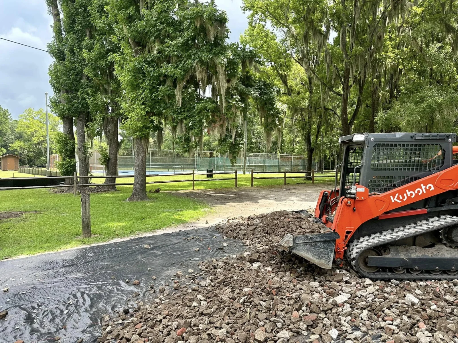 Compact track loader spreading aggregate during site preparation